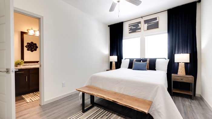 Apartments for Rent in Boerne, TX - Garden Creek - Furnished Bedroom with Wood-Style Flooring, Window, Ceiling Fan, and In-Suite Bathroom
