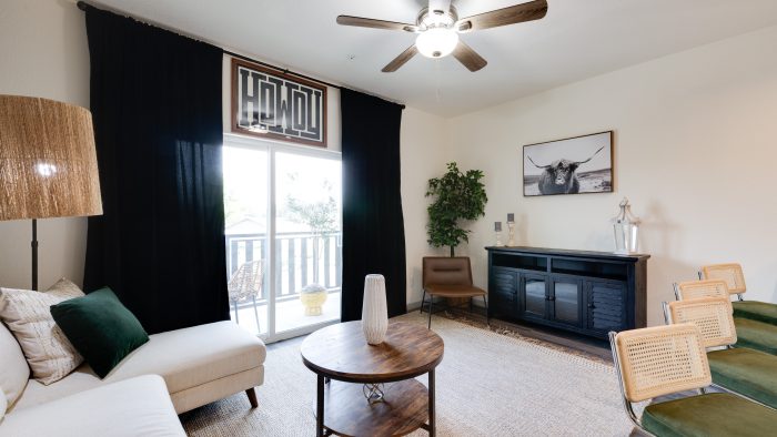 Two-BR Apartments in Boerne, TX - Garden Creek - Furnished Living Room with Wood-Style Flooring, Ceiling Fan, and Sliding Glass Door to Patio.