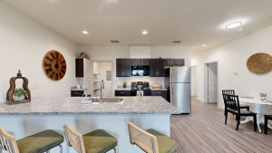 a kitchen with a large island and bar stools at The Garden Creek Apartments