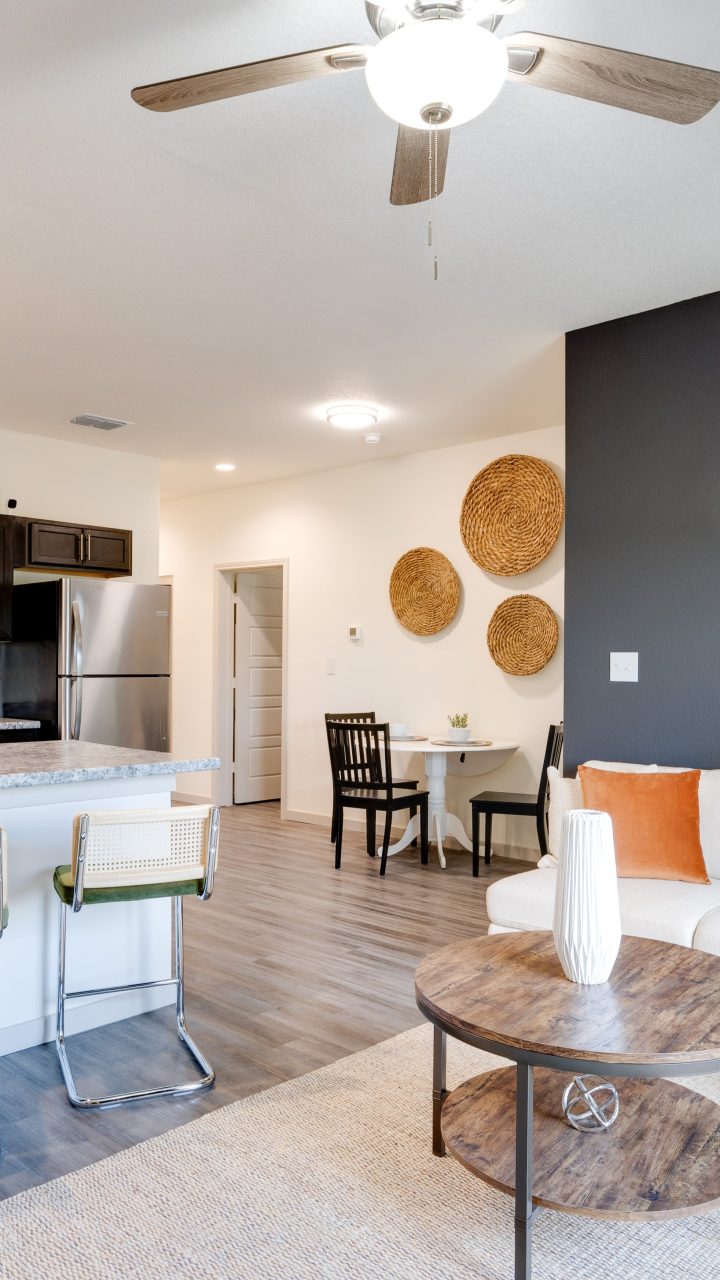 a living room and kitchen area with a ceiling fan at The Garden Creek Apartments