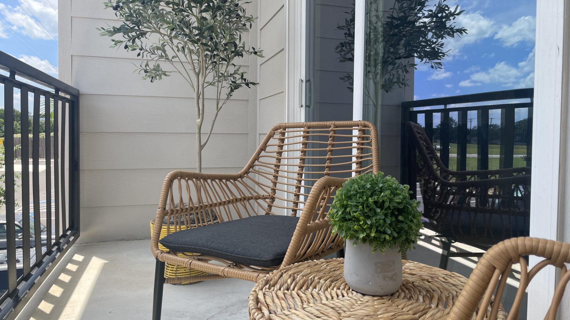 a wicker chair and table on a balcony at The Garden Creek Apartments