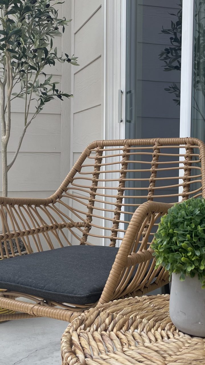 a wicker chair and table on a balcony at The Garden Creek Apartments