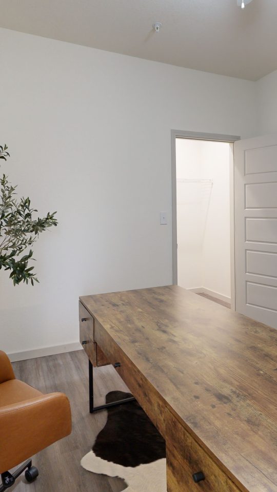 a room with a desk and chair in it at The Garden Creek Apartments