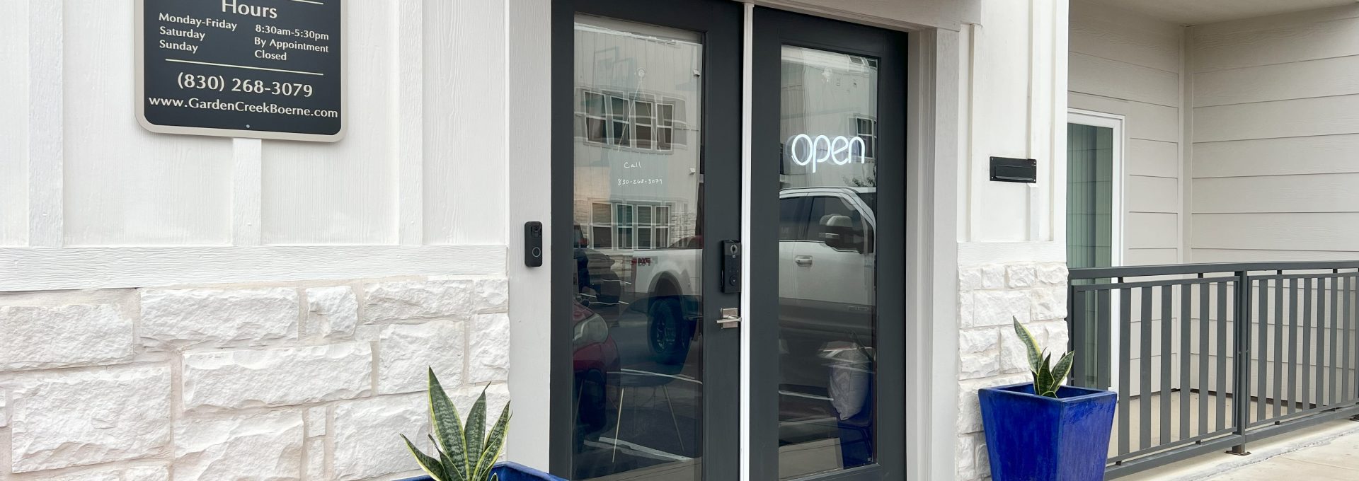 the entrance to a building with two blue potted plants at The Garden Creek Apartments
