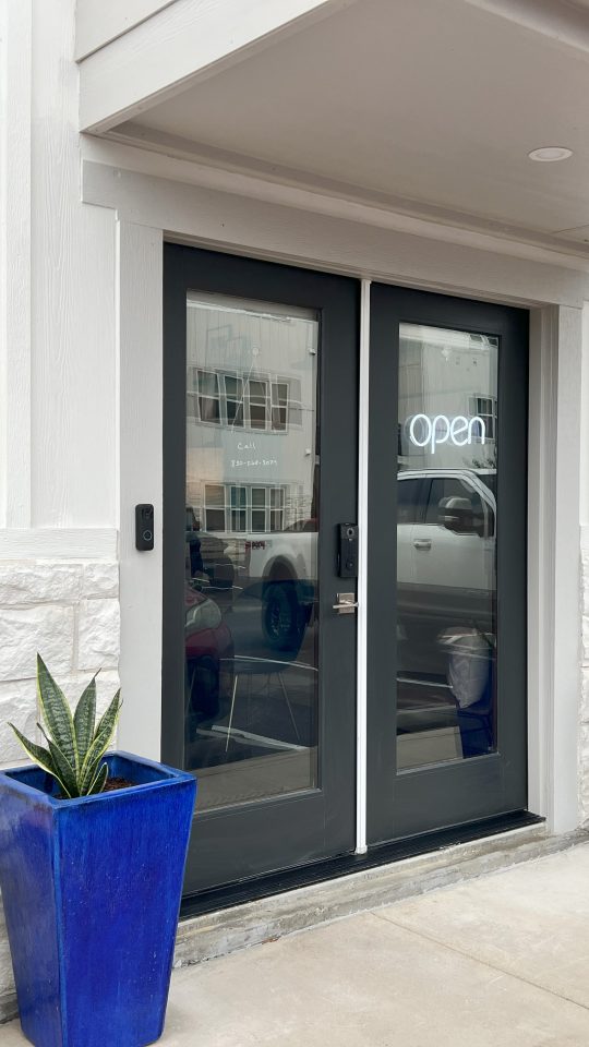 the entrance to a building with two blue potted plants at The Garden Creek Apartments